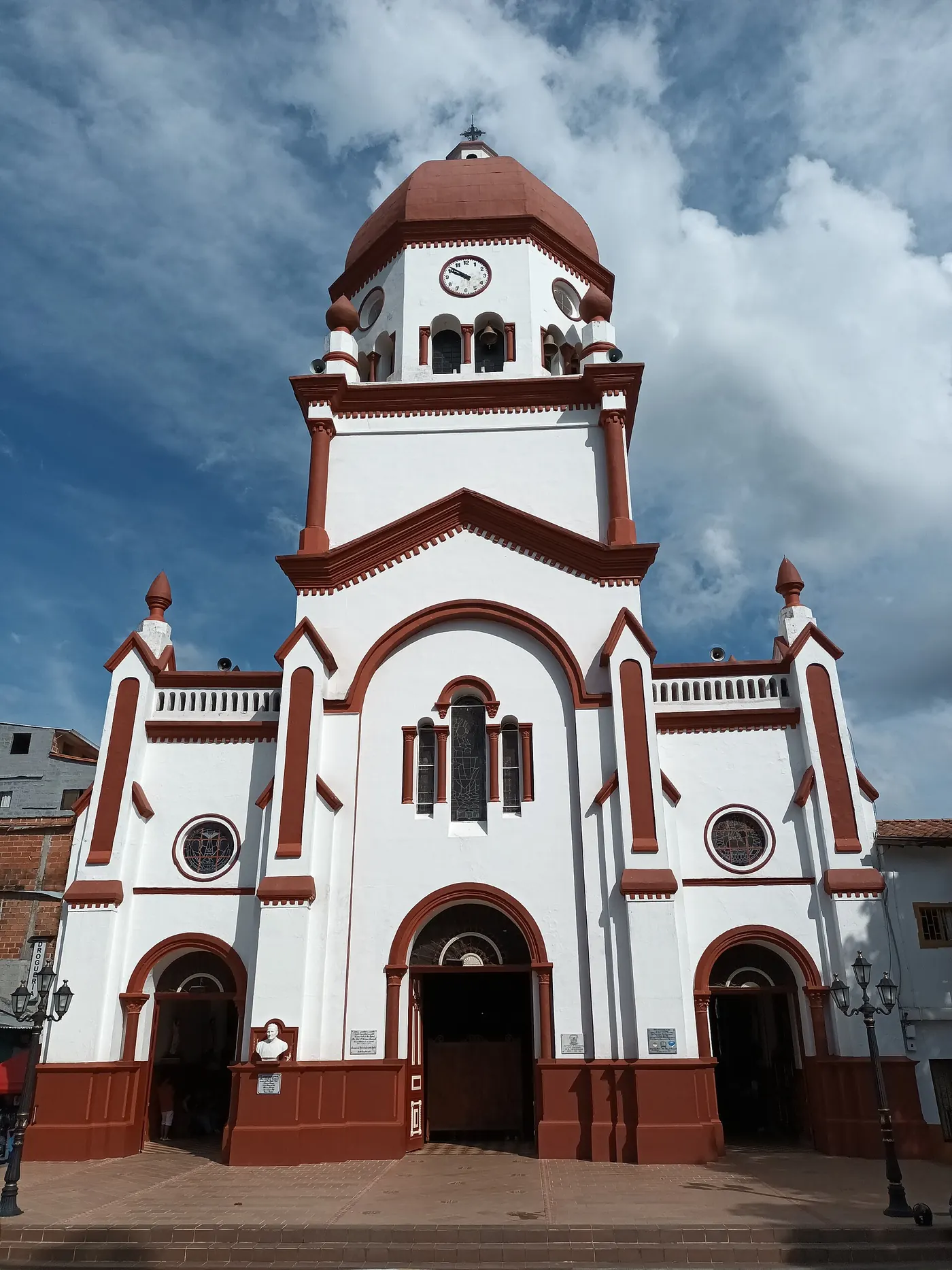 Fachada blanca con detalles rojizos y cúpula de la iglesia de San Rafael Arcángel